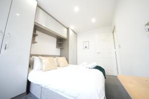 a white bedroom with a white bed in it at The Hatton Rooms in New Bedfont