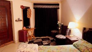 a bedroom with a bed and two chairs and a window at muree cottage in Murree