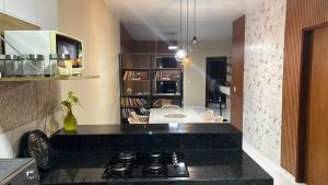 cocina con encimera negra y sala de estar. en Casa aconchegante no litoral do Piauí, ao lado da Iesvap e Assaí Supermercado, en Parnaíba 10 fotos más