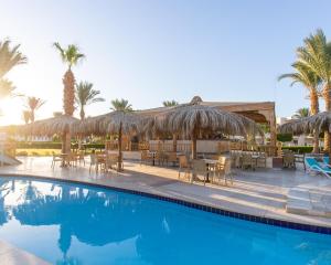 un complexe avec une piscine avec chaises longues et parasols dans l'établissement Hurghada Long Beach Resort, à Hurghada