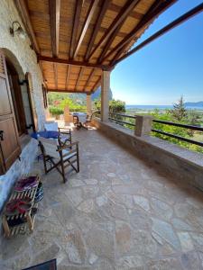 un patio con tetto in legno, tavolo e sedie. di Red Rock & Sea House a Leonidion (Leonidio)