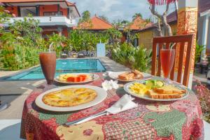 a table topped with plates of food next to a pool at Villa Jepun Lovina in Lovina
