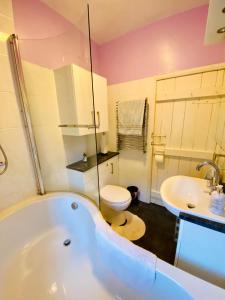 a bathroom with a tub and a toilet and a sink at School House in Patterdale