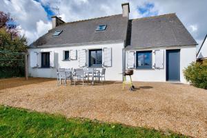 a house with chairs and a table in front of it at Maison pour 6 avec terrasse et jardin in Guissény