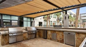 an outdoor kitchen with stainless steel appliances on a patio at Lookout Luxe 2BR | King + Q/Q Bunk | Shuffleboard in Audelia