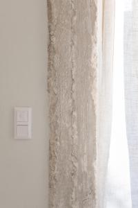 a white wall with a curtain and a window at Atla Living Athens in Athens