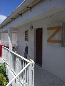 a white house with a wooden door and a porch at Les jardins de VALENTIN in Le Gosier