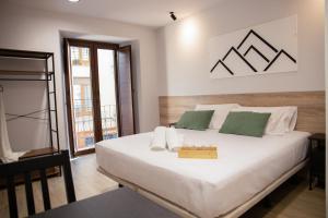 a bedroom with a large white bed with green pillows at Inkigo Rooms in Jaca
