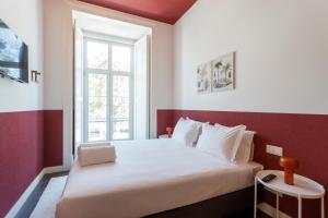 a bedroom with a white bed and a window at Gloria Guesthouse in Lisbon