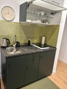 a kitchen with a sink and a clock on the wall at Apartament Trocera 2 in Zabrze