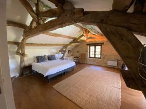 a bedroom with a bed in a room with wooden beams at Le Domaine de Camberoux La Petite Longère in Saint-Marcel-du-Périgord