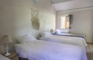 Dos camas en una habitación con paredes blancas. en Le Barry, en Tulette