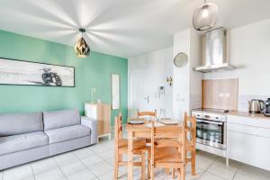 eine Küche und ein Wohnzimmer mit einem Tisch und einer Couch in der Unterkunft La Pause Urbaine - Proximité Lyon - Terrasse Privée in Vaulx-en-Velin
