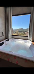a bath tub in a room with a window at Pousada Varandas de Minas in Monte Verde +43 photos