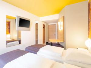a hotel room with two beds and a flat screen tv at B&B Hotel Heilbronn in Heilbronn +20 photos