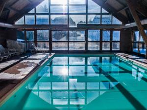 a swimming pool with blue water in a building with windows at Chalet rénové 6 pers, TV connectée, WiFi, parking, animaux admis - FR-1-504-480 in Le Dévoluy +16 photos