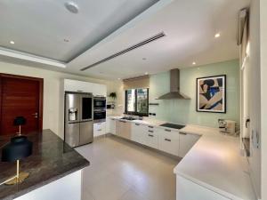 une cuisine avec des armoires blanches et un comptoir dans l'établissement Bangtao villa with pool & rooftop terrace, à Ban Thalat Choeng Thale