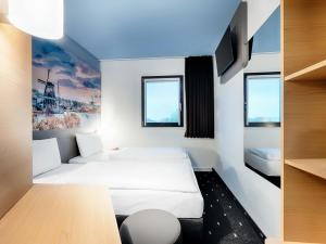 a hotel room with two beds and a tv at B&B Hotel Amsterdam-Zaandam in Zaandam