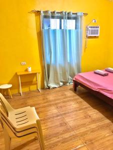 Habitación con cama, silla y ventana en Three Sister's Inn, en Siquijor