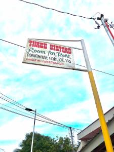 una señal en un poste frente a un edificio en Three Sister's Inn, en Siquijor