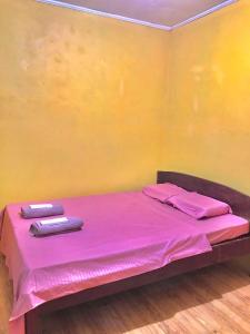 Una cama con sábanas rosas y dos toallas. en Three Sister's Inn, en Siquijor