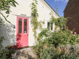 a pink door on a white house with flowers at Over Village Studio in Over