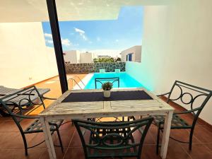 Una mesa y sillas de madera en un balcón. en Villa Papagayo Mirage, en Playa Blanca