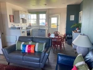 un salon avec un canapé et une cuisine dans l'établissement Cradle Cottage, à Crail