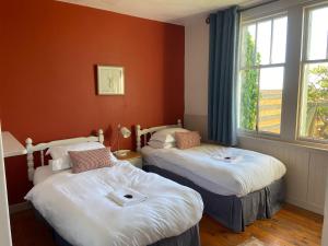 Ce lit se trouve dans un dortoir doté de murs orange et d'une fenêtre. dans l'établissement Cradle Cottage, à Crail