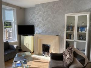 a living room with a fireplace and a tv at Nairoo in Balloch