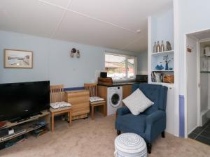 a living room with a tv and a blue chair at Scarba in Balvicar