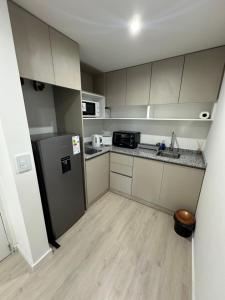 eine kleine Küche mit weißen Schränken und einem Kühlschrank in der Unterkunft MOVISTAR ARENA PREMIUM THAMES 56 7 piso 713 Cocheras y Seguridad in Buenos Aires