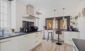 a kitchen with white cabinets and a sink at Maison de ville in Saint-Pol-de-Léon