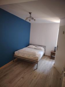 a bed in a room with a blue wall at La Casa Beaujolaise in Charnay +2 photos