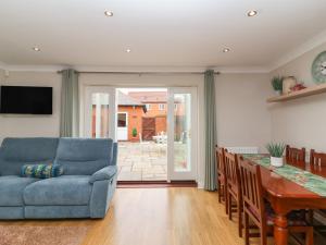 a living room with a blue couch and a table at Pilgrims Rest in Worle