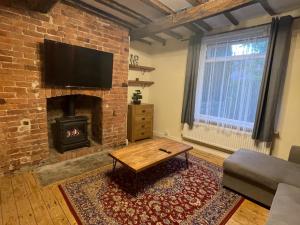 een woonkamer met een bakstenen muur en een open haard bij Mallison Cottage in Stalybridge