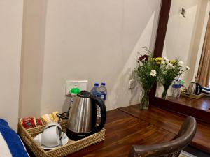 a tea kettle on a table with flowers and water bottles at Brinkhouse Guesthouse , Unawatuna beach in Unawatuna