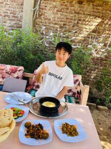 a young man sitting at a table with food at Tokyo House Luxor in Luxor