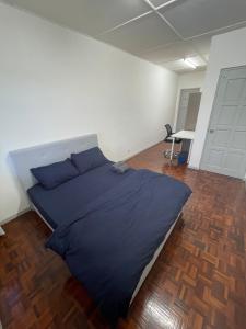a large blue bed in a room with a wooden floor at Authentic Local Terrace House in Kuching in Kuching