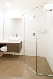 a glass shower in a bathroom with a sink at Posthouse Motor Lodge in Goulburn