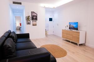 Una sala de estar con un sofá negro y un televisor. en Your Home in Tenerife, Alojamiento ideal con wifi y parking en Güímar, en Puertito de Güímar