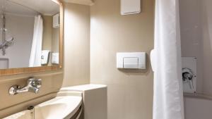 a bathroom with a sink and a mirror and a tub at Premiere Classe Bourges in Bourges