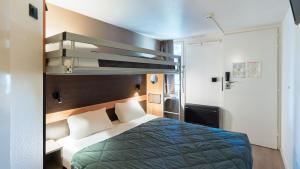 a hotel room with a bed with a blue blanket at Premiere Classe Bourges in Bourges