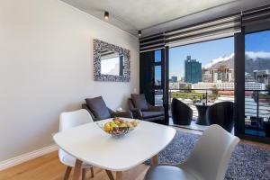 ein weißes Esszimmer mit Tisch und Stühlen und Aussicht in der Unterkunft The Docklands 509 by CTHA in Kapstadt
