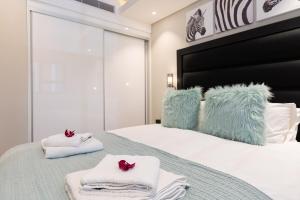 Schlafzimmer mit einem Bett mit Handtüchern und einem Zebra-Kopfteil in der Unterkunft The Docklands 509 by CTHA in Kapstadt