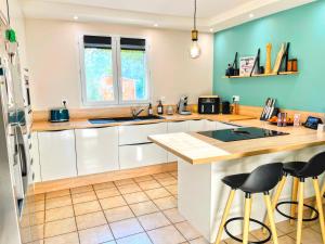 a kitchen with white cabinets and a blue wall at Le Petit Paradis Lescurien in Lescure-dʼAlbigeois