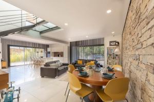 a living room with a wooden table and yellow chairs at Albaé - Climatisé - Piscine - Parking - Provence in Allauch