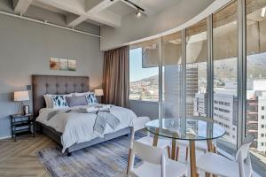Un dormitorio con una cama y una mesa de cristal. en D'Luxe on Thibault by CTHA, en Ciudad del Cabo