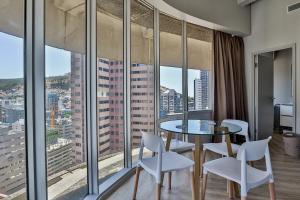 Habitación con mesa, sillas y ventanas grandes. en D'Luxe on Thibault by CTHA, en Ciudad del Cabo
