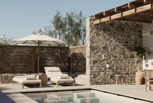 a patio with a pool and chairs and an umbrella at Elion Villas in Kos Town